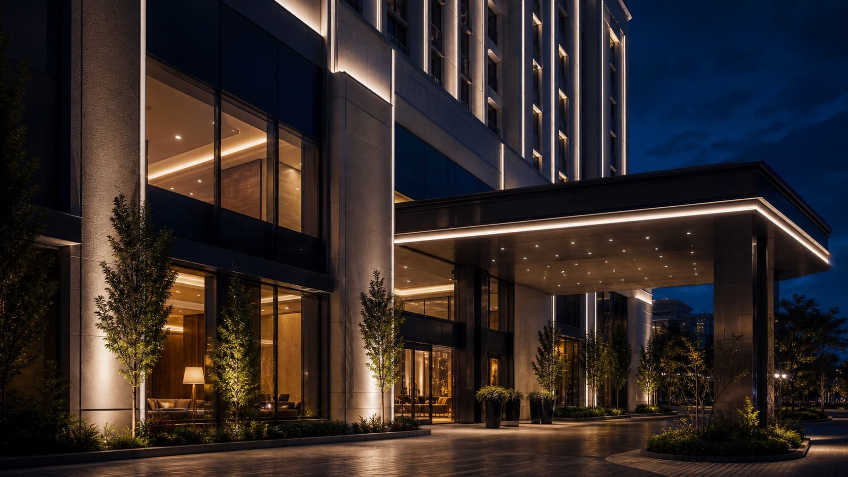 Upscale hotel exterior at night with facade grazing and illuminated canopy lighting
